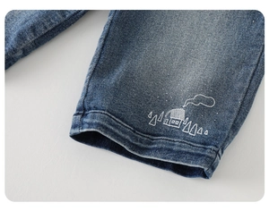 Detail of dark blue denim cuff with white house and tree embroidery for kids' pants
