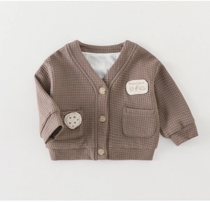 Dettaglio del cardigan in maglia a nido d'ape per neonati con bottoni in legno e tasche