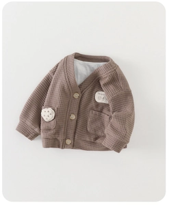Dettaglio macro del cardigan marrone in maglia a nido d'ape con toppa a biscotto