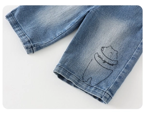 Close-up of baby boy denim jeans showing washed fabric and cute bear embroidery detail