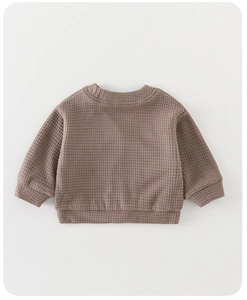 Dettaglio del tessuto a nido d'ape e dei polsini a costine di questo maglione marrone per neonati