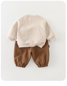 Close-up of beige sweatshirt ribbed cuffs and brown jogger pants with wash label