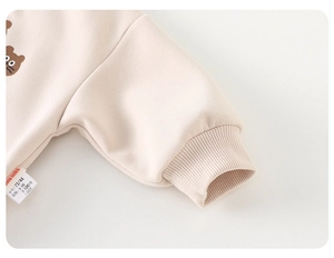 Detail of ribbed cuffs and soft cotton blend fabric on kids beige bear sweatshirt
