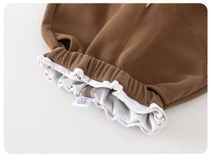 Detail of baby boy brown pants elastic waistband with white drawstring and inner stitching