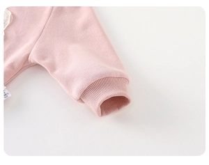 Detail of pink knitted sleeve with soft ribbed texture and delicate lace embroidery
