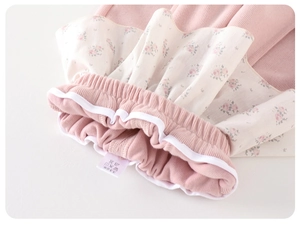 Close-up of pink ribbed fabric and floral ruffles with a clear fabric care label