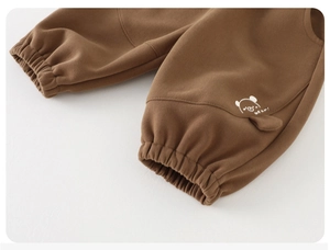Detailed close-up of brown toddler joggers featuring bear embroidery and ribbed ankle cuffs