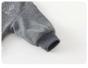 Detail of grey waffle knit sleeve with ribbed cuff and small white tree embroidery