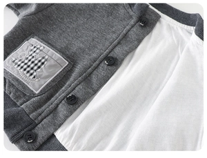 Close-up of grey knitted boys' cardigan featuring cute bird patch and black buttons