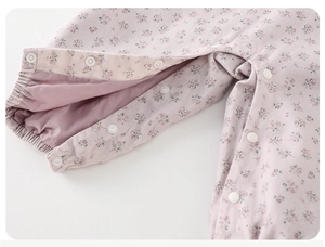 Close-up of pink floral baby romper featuring white snap buttons and elastic cuffs