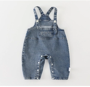 Détail de la salopette en jean pour bébé avec poche brodée et boutons-pression pratiques