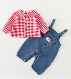 Détail de la salopette en jean pour bébé avec dentelle et chemise à carreaux rouge et blanc
