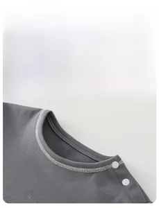 Detail of dark grey kids' t-shirt collar with shoulder snap buttons and neat stitching