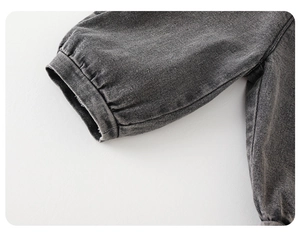 Detail of the sleeve cuffs on a grey denim jacket featuring elastic pleats and washed texture