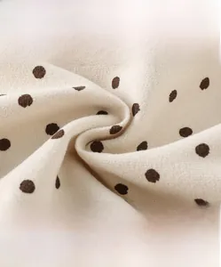 Detail of high-density cream cotton fabric with brown polka dots for soft kids pants