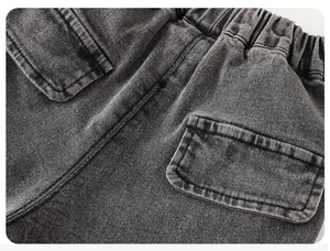 Detail view of elastic drawstring waistband and large pocket on dark grey boy's denim pants