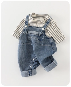 Détail de la salopette en jean pour bébé avec broderie café et t-shirt à rayures