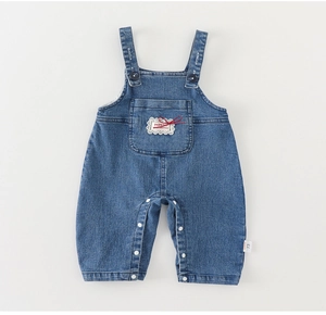 Détail de la salopette en jean bébé avec poches en dentelle et étiquette de taille 73