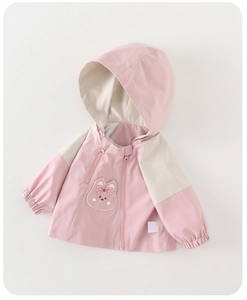 Close-up of pink and beige kids windbreaker with embroidered cartoon bunny and bow detail