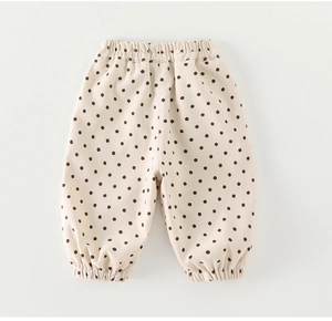 Detailed view of beige polka dot baby trousers with elastic waist and ruffled cuffs