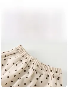 Close-up of elastic waistband on cream-colored polka dot baby trousers with soft fabric