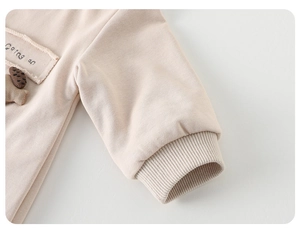Detail von Rippbündchen und Baumwollstoff mit Going on Stickerei auf Baby-Strampler