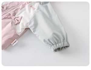 Dettaglio della giacca a vento da bambina con ricamo a fiocco rosa e polsini elastici