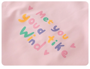 Detail of pink fabric featuring colorful artistic font and heart print on kids jacket