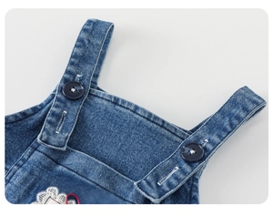 Vue détaillée des bretelles en jean avec boutons ronds et bordure en dentelle brodée