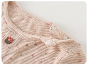 Détail de gilet en tricot rose avec broderie florale et boutons à l'épaule