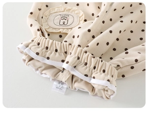Detail of baby polka dot pants featuring elastic waist with lace trim and happy patch