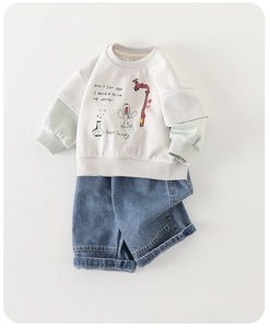 Flat lay of cream toddler sweatshirt with cartoon print and blue denim jeans set