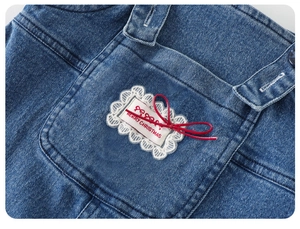 Détail de poche en jean bleu avec dentelle blanche, nœud rouge et imprimé de Noël