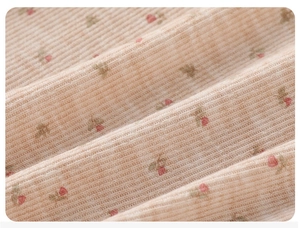 Détail du tissu en maille côtelée avec de délicates fleurs roses et vertes sur beige