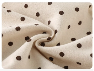 Macro shot of soft beige fabric featuring dark brown polka dots and grainy texture