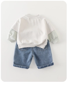 Detail view of baby casual outfit with cream sweatshirt and blue denim shorts set