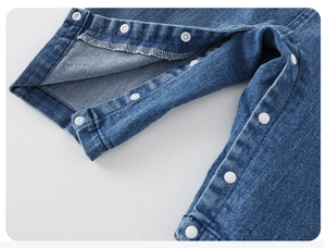 Gros plan sur les boutons-pression blancs du pantalon en jean bleu pour bébé et nouveau-né