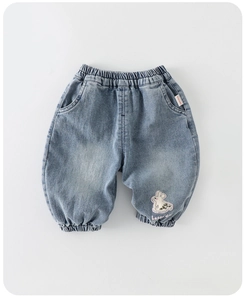 Détail du jean bleu montrant la taille élastique et une broderie lapin avec texte happy day