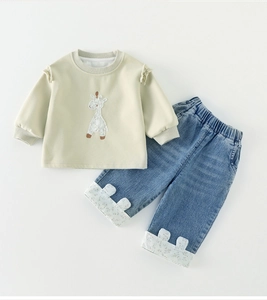 Detail of baby girl outfit showing giraffe embroidery and bunny ear denim cuffs