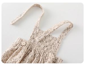 Detail eines Baby-Blumen-Outfits mit verstellbaren Trägern und weißen Knöpfen