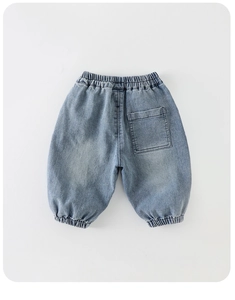 Détail d'un jean pour enfant bleu clair avec taille élastique et poche sur fond blanc