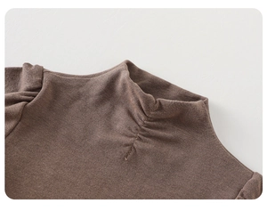 Close-up of brown knitted top featuring a chic mock neck and shirring details