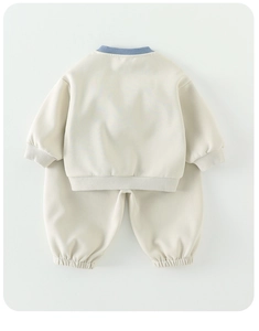 Flachbild-Detail eines Kleinkinder-Sweatshirt-Sets in Creme mit blauem Rippstrick-Ausschnitt