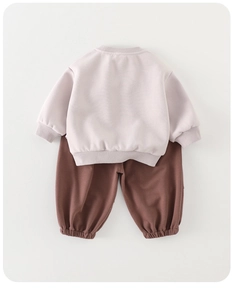 Detailed view of the ribbed cuffs on light pink sweatshirt and brown joggers set