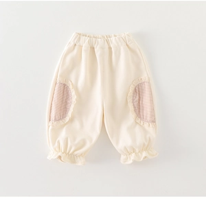 Détail du pantalon écru pour enfant avec poches à carreaux marron et finitions dentelle