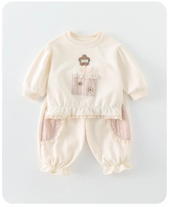 Détail de l'ensemble tricoté pour bébé avec broderie florale et finitions dentelle