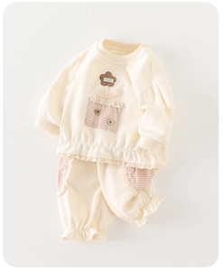 Détail d'un ensemble sweat beige pour bébé fille avec fleurs et poches en dentelle