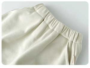 Detaillierte Nahaufnahme von elastischem Bund und Seitentasche an cremeweißer Babyhose