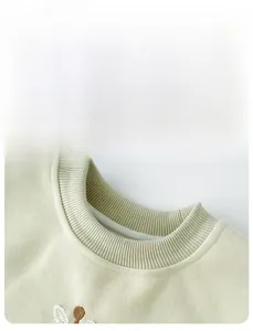 Detail of baby girl mint green sweatshirt showing ribbed neckline and fine embroidery