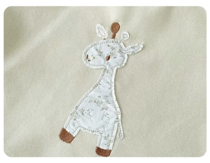 Detail of baby sweatshirt featuring giraffe patchwork embroidery with floral fabric